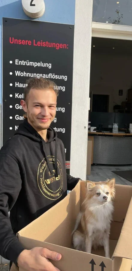 Fairwerter Haus entrümpeln Mitarbeiter mit Kiste und Hund Coco drin